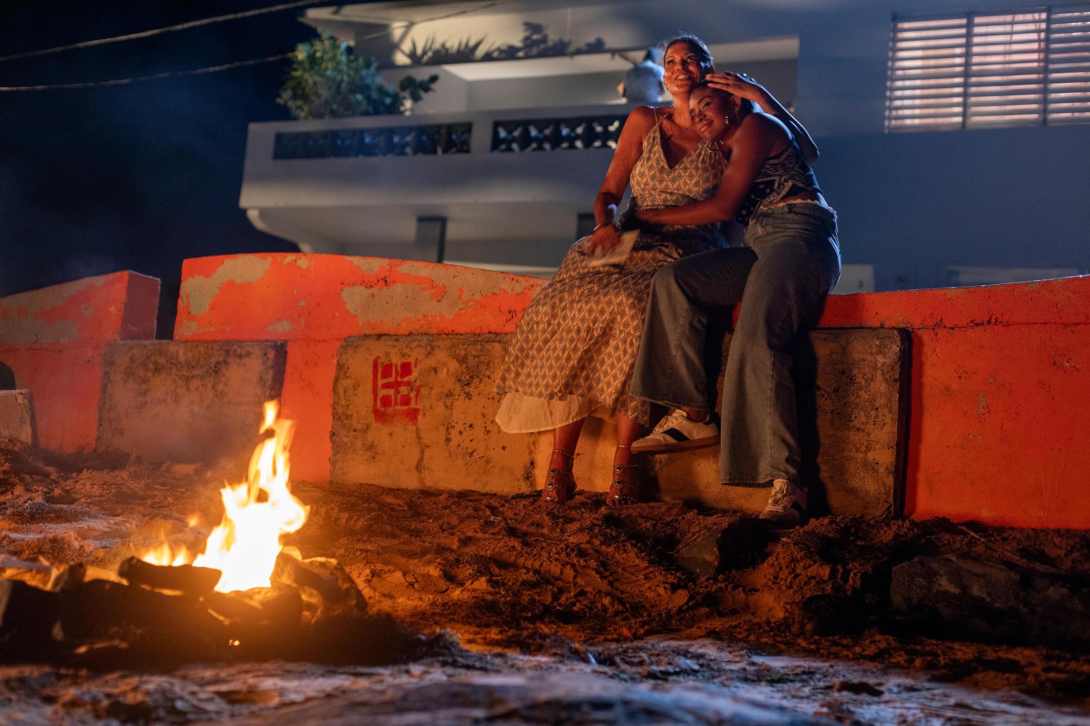 Two characters embracing beside a fire in Hurricane Seasons
